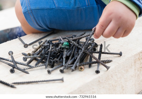 Boy playing with nails on a\
table