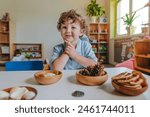 Boy playing with natural toys, seashells, pine cones, feathers in a kindergarten or daycare center. Selective focus