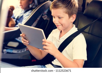 Boy Playing On A Digital Tablet In The Car