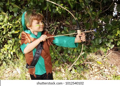 Boy playing outdoors with a bow, aiming with one eye shut. Dressed for Purim party - Shutterstock ID 1012540102