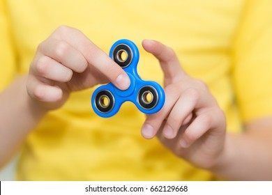 A boy is playing a popular toy fidget spinner in his hands. Stress relief. Anti stress and relaxation fidgets, spinner for tired people. Boy playing with a fidget spinner.