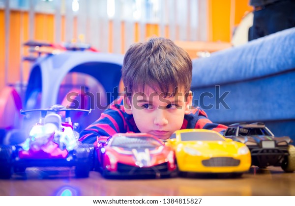 boy playing with a radio car at home. plastic radio\
battery cars, various fancy models. home entertainment. child\
playing with toys.