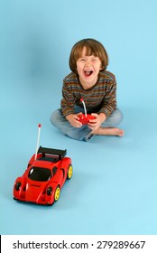 Boy Playing With A Remote Controlled Toy Car On Blue Background