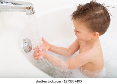 Boy Playing With Running Water In The Tub, While Bathtub Fills Up. 