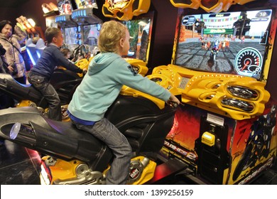 Boy Is Playing Slot Machines. Moscow 2012. Kid Playing Arcade Simulator Machine At An Amusement Park. Boy On Amusement Bike At Indoor Playground.