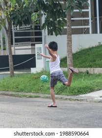 A Boy Playing Soccer On The Street In Front Of His House, Jombang, East Java INDONESIA, 10th June 2021