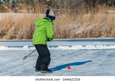 Boy Playing Street Hockey On Frozen Lake