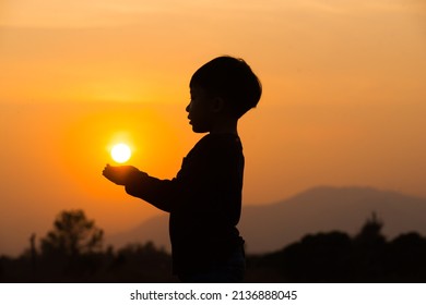 A Boy Playing With The Sun At Sun Set. Silhouette Picture With Orange Sun Set Sky. 