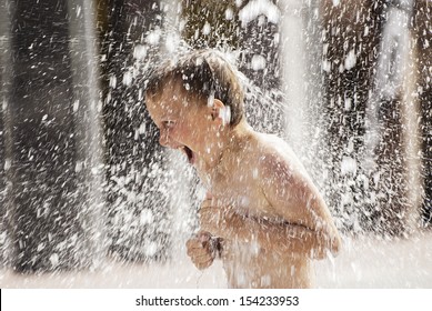 A Boy Playing With Water In Park Fountain. Hot Summer.