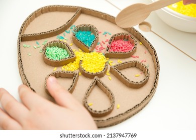 Boy Plays With Green Color Rice. Implement For Children To Develop Fine Motoric Skills Through Play. DIY Toy To Learn Hand - Eye Coordination.