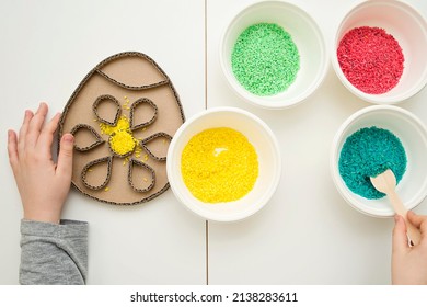 Boy Plays With Green Color Rice. Implement For Children To Develop Fine Motoric Skills Through Play. DIY Toy To Learn Hand - Eye Coordination.