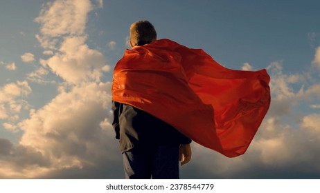 Boy Plays Superhero in red cape, Children dream. Child hero in red cloak looks at sun sky. Happy child playing super hero, outdoors. Bold child winner in red raincoat, nature. Brave boy in red cloak - Powered by Shutterstock