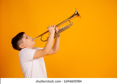 A boy plays the trumpet. Beautiful teenager boy plays trumpet musical instrument