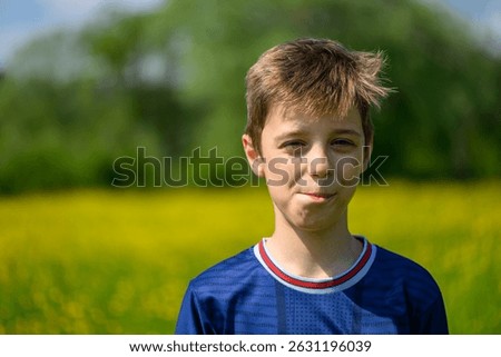 The boy is posing in Field with Meadow Buttercup (Ranunculus acris).