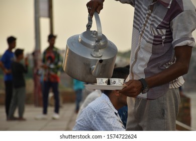 A Boy Pouring Tea In Cups From Kettle