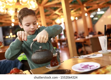 Boy Pouring Tea Into Turkish Glass In Restaurant