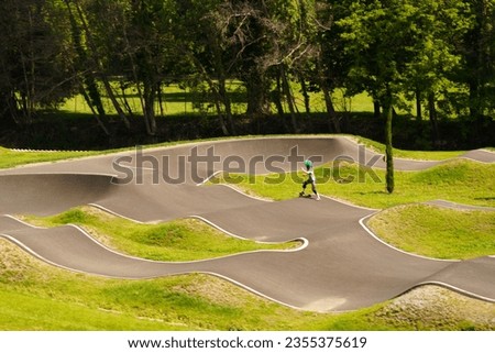 A boy in a protective helmet and knee pads learn to ride a skateboard on a special track. Sport activity concept. Background unsharp image.