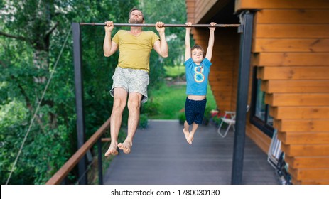 A boy pulls himself up on the bar. The son and father go in for sports. Sports family in training.The father teaches his child to achieve goals. Summer family outdoor sports workouts in the country. - Powered by Shutterstock