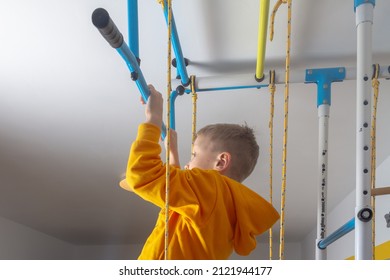 The Boy Pulls Himself Up On The Horizontal Bar At The Sports Complex At Home In The Room.