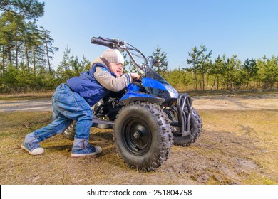 The Boy Pushes Quad Bike In The Woods