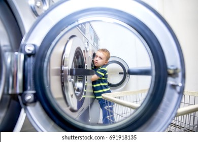 Boy Puts Clothes In A Washing Machine In A Public Laundry. Diligent Child Helps With Washing In Laundromat