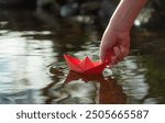 a boy puts a paper boat into the water