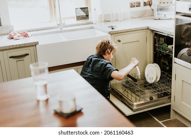 Boy putting dish to dishwasher, household chores for kids