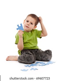 Boy with puzzles scratches his head and thinking