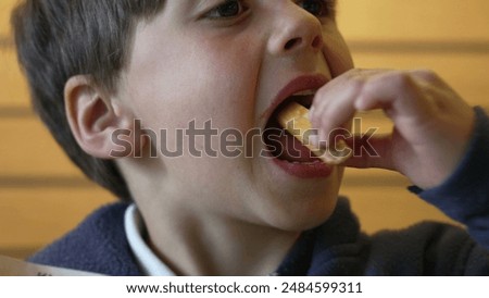 Boy quickly pulls away a hot fry from his mouth, expressing surprise and slight discomfort. captures a candid moment of tasting hot food, highlighting the sensory experience and reaction