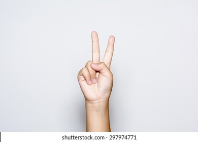 Boy raising two fingers up on hand it is shows peace strength fight or victory symbol and letter V in sign language on white background.
