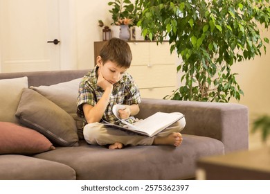 
A boy is reading a book while sitting on the couch