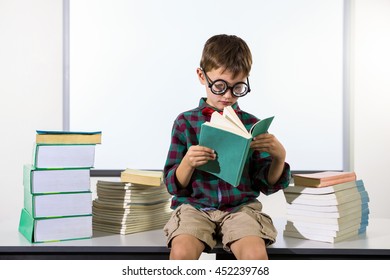 Boy reading book while sitting on table in classroom