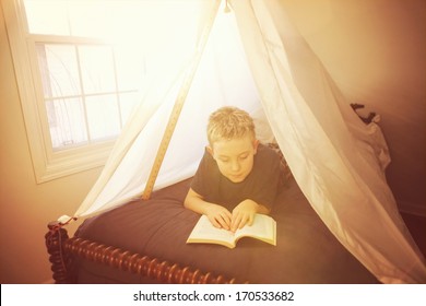 Boy reading in a fort made of sheets