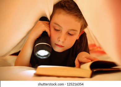 Boy reading under the covers