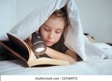 Boy reading under the covers