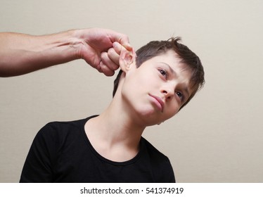 Boy Receives Physical Punishment From The Adult. Have Grabbed By An Ear.