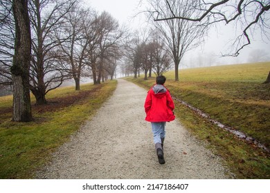 Boy in a red jacket walking on a path on a cloudy day
