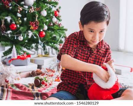 boy in a red shirt is happy and funny to celebrate Christmas with christmas tree