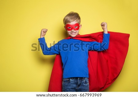 Boy in red super hero cape and mask. Studio portrait over yellow background