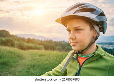 Boy To Ride Bicycle. Happy Cute Child In Helmet Learn To Riding A Bike In Park On Green Meadow In Summer Day At Sunset Time. Family Weekend. 4K Video Slow Motion