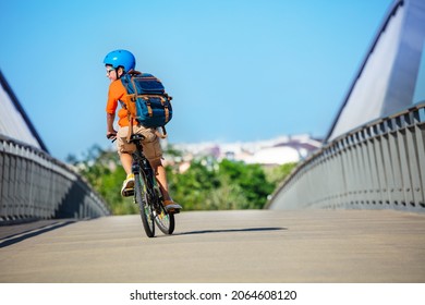 Boy ride on the bicycle from school with backpack and in blue helmet view from back - Powered by Shutterstock