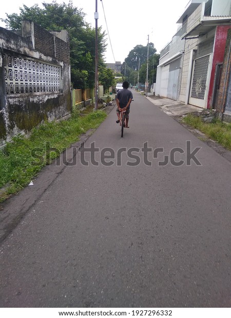 a boy rides a bicycle in the\
city of solo, Central Java province, Indonesia on March 2,\
2021