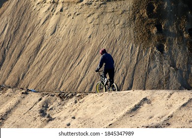 boy rides a bicycle in a sand pit