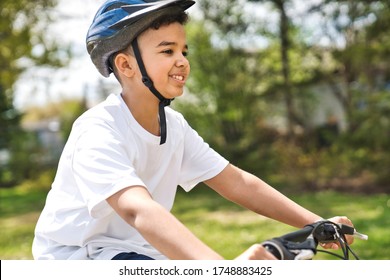 A Boy Riding Bike Wearing A Helmet Outside