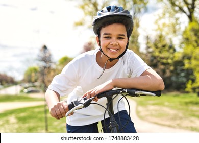 A Boy Riding Bike Wearing A Helmet Outside