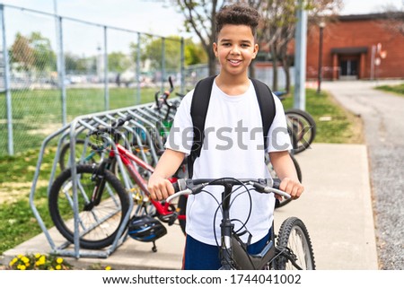 A boy riding bike wearing a helmet outside at school playground