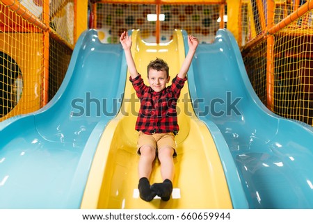 Boy riding from childrens slides on playground