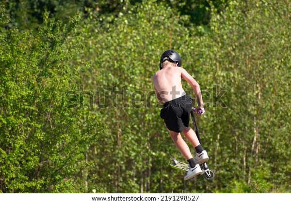 boy riding a stunt\
scooter on a hot day