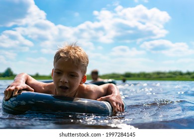 Boy With A Rubber Ring Floats In The Summer. Child Swims In The Lake In Summer. Summer Children's Entertainment