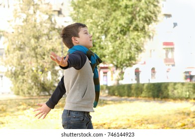 Boy running across the yard from the joyful feeling of freedom. A long scarf is tied around the boy's neck